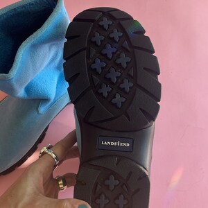 May include: Light blue Lands' End boot with a black sole. The sole has a textured pattern. The boot is made of a soft material and has a zipper. The Lands' End logo is visible on the sole.