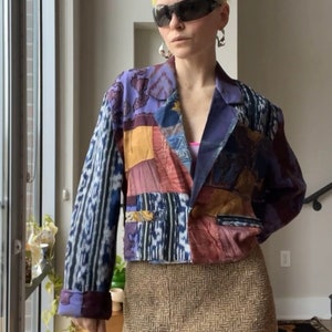 May include: A cropped, multi-colored patchwork blazer with a blue base and a brown herringbone skirt.