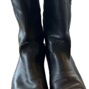 Puede incluir: Un par de botas vaqueras de cuero negro con punta puntiaguda y diseño de calcetín.