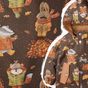 Puede incluir: Una gabardina marrón con capucha presenta un patrón repetido de animales del bosque que llevan impermeables y sostienen paraguas. Los animales incluyen un zorro, un tejón, un conejo y un gato. El fondo es de color marrón con un patrón de lunares blancos.