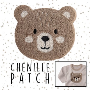 Könnte beinhalten: Ein brauner Chenille-Patch mit einem Bärenkopf-Design. Der Patch befindet sich auf einem weißen Hintergrund mit kleinen braunen Punkten. Der Text "CHENILLE PATCH" befindet sich unter dem Patch.
