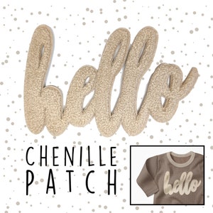 Könnte beinhalten: Ein goldfarbener Chenille-Aufnäher mit dem Wort "hello" in kursivschrift. Der Aufnäher ist auf einem weißen Hintergrund mit braunen Punkten und auf einem braunen Langarmshirt zu sehen.