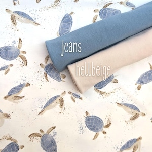 Könnte beinhalten: Zwei Stoffmuster, eines hellblau und eines hellbeige, mit den Worten "jeans" und "hellbeige" bedruckt. Der Stoff liegt auf einem weißen Hintergrund mit einem Muster aus blauen Meeresschildkröten.