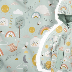 Op de afbeelding: Een lichtblauwe stof met een herhalend patroon van regenbogen, zonnen, wolken, bomen, bijen en gieters. De tekst "hello", "happy", "sunshine" en "rainbow" is verspreid over het hele patroon.