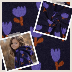 Könnte beinhalten: Ein dunkelblaues Kleidungsstück mit Kapuze aus einem strukturierten, flauschigen Fleece-Material. Der Stoff zeigt ein sich wiederholendes Muster aus violetten tulpenförmigen Blumen mit orangefarbenen Stielen. Das Design ist durchgehend.