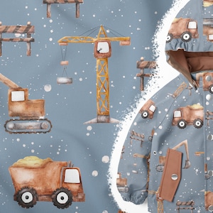 Könnte beinhalten: Eine blaue Kinderjacke mit einem sich wiederholenden Muster aus Baufahrzeugen, Kränen und Straßensperren. Die Fahrzeuge sind braun und gelb mit weißen schneeähnlichen Punkten auf dem Hintergrund.