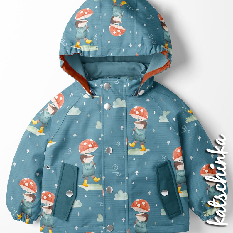 Puede incluir: Una gabardina azul para ni&ntilde;os con un patr&oacute;n de setas y lluvia. La gabardina tiene capucha y dos bolsillos. El patr&oacute;n presenta un personaje de dibujos animados sosteniendo un paraguas de seta.