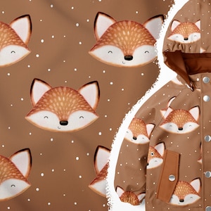 Op de afbeelding: Een bruine capuchonjas met een herhalend patroon van cartoon-vossengezichten. De jas heeft een bruine rits en bruine knopen.