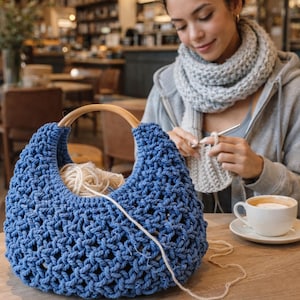 May include: A deep blue crochet handbag featuring a thick, knotted open-weave pattern and a rounded wooden handle. The bag contains a ball of light beige yarn, with a single strand extending outward from the interior of the blue textile structure.