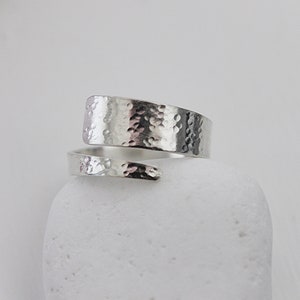 May include: A silver hammered wrap ring. The ring is made from a single piece of metal that is wrapped around the finger.