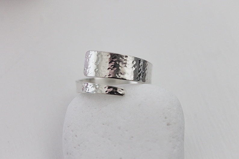 May include: A silver hammered wrap ring. The ring is made from a single piece of metal that is wrapped around the finger.