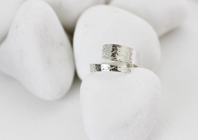 May include: A silver hammered wrap ring. The ring is made from a single piece of metal that is wrapped around the finger.