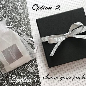 May include: Two options for packaging a gift. Option 1 is a white organza bag with a label that says "Jewellery By Doreen". Option 2 is a black gift box with a silver ribbon tied in a bow.