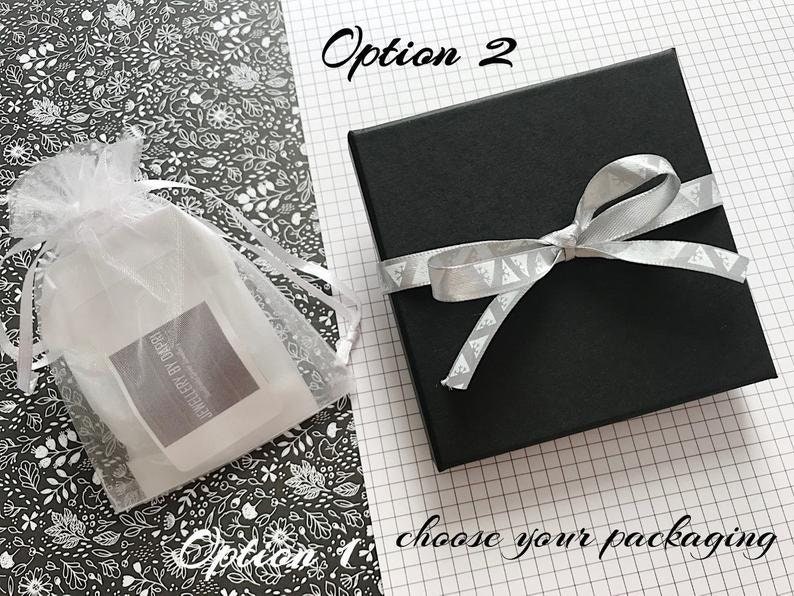 May include: Two options for packaging a gift. Option 1 is a white organza bag with a label that says "Jewellery By Doreen". Option 2 is a black gift box with a silver ribbon tied in a bow.