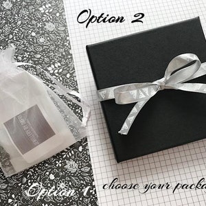 May include: Two options for packaging a gift. Option 1 is a white organza bag with a label that says "Jewellery By Doreen". Option 2 is a black gift box with a silver ribbon tied in a bow.