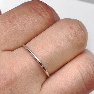 May include: A simple silver band ring worn on a finger.