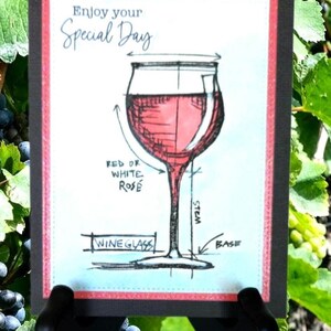 May include: A greeting card with a sketch of a wine glass filled with red liquid. The card has the text "Enjoy your Special Day" at the top. The words "Red or White Rose", "Stem", "Base", and "Wine Glass" are also written on the card.