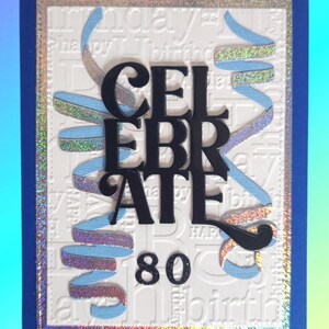 May include: A rectangular greeting card with a dark blue border and a white embossed background featuring the repeated text "happy birthday". The card displays the black text "CELEBRATE" and "80" with light blue holographic ribbon accents.