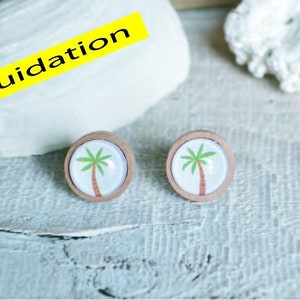 May include: A pair of wooden earrings with a white background and a green palm tree design.