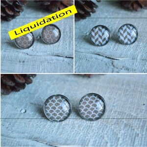 May include: A set of four pairs of earrings featuring different geometric patterns. The earrings are made of metal and have a clear glass cabochon with a white and grey pattern. The patterns include a honeycomb, chevron, and two different scale patterns.