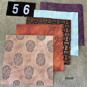 May include: A collection of embossed leather squares in various colors and patterns. Designs include sugar skulls, running horses, and geometric textures. The squares are approximately 10x10 inches in size. A black sign displays the number 56.