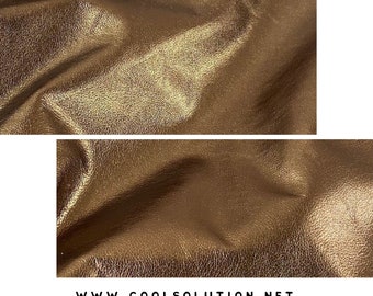 May include: Close-up of a metallic gold leather fabric with a textured surface. The fabric has a subtle sheen and a soft, supple feel.