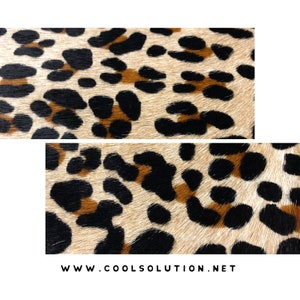 May include: Close-up of a beige fabric with a black and brown leopard print pattern.