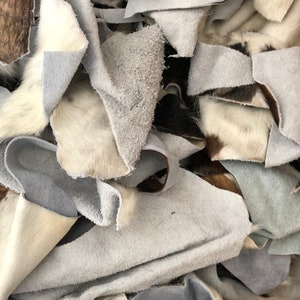 May include: A pile of white, brown, and black cowhide leather scraps. The leather is soft and supple, and it is perfect for crafting projects.