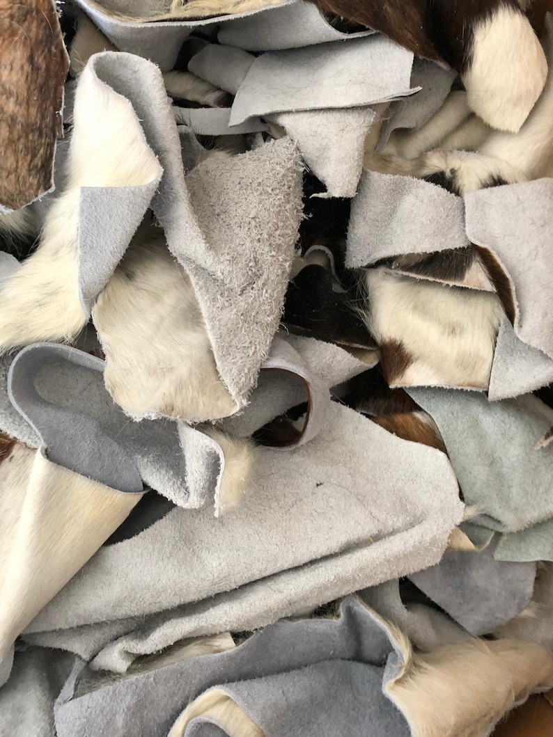May include: A pile of white, brown, and black cowhide leather scraps. The leather is soft and supple, and it is perfect for crafting projects.