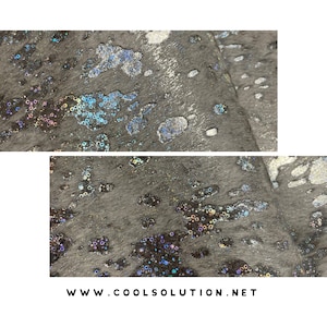 May include: Close-up of a textured, dark gray fabric with iridescent, sequin-like embellishments. The fabric has a mottled appearance with patches of silver and colorful, shimmering accents. The website address "WWW.COOLSOLUTION.NET" is visible at the bottom.