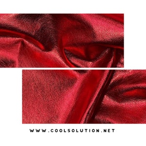 May include: Close-up of a red metallic fabric with a textured surface. The fabric is folded and draped, creating a soft, flowing look.