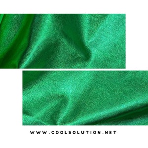 May include: Close-up of a green, textured, metallic fabric. The fabric has a subtle shimmer and is folded in a way that shows its texture.
