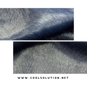May include: Close-up of a dark blue, soft, fuzzy fabric with a slight sheen. The fabric has a short pile and a smooth texture.