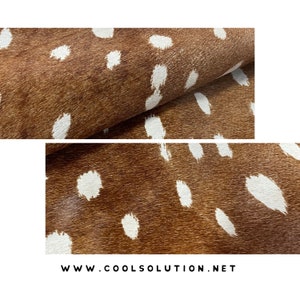 May include: Close-up of a brown and white spotted hide. The hide has a natural texture with irregular white spots against a brown background. The image shows the hide folded over, revealing its texture.