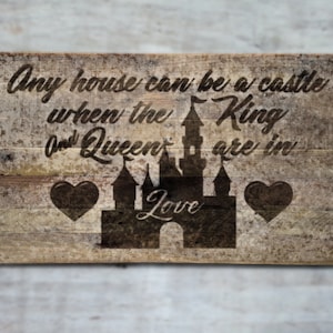 May include: A wooden sign with a distressed finish featuring a silhouette of a castle with the text "Any house can be a castle when the King and Queen are in love".