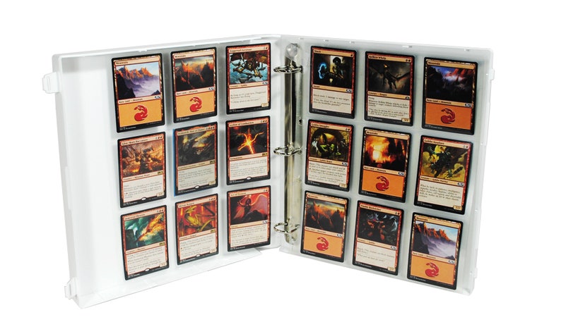 May include: A white binder with clear plastic sleeves holding trading cards. The cards feature fantasy artwork with dragons, monsters, and landscapes.