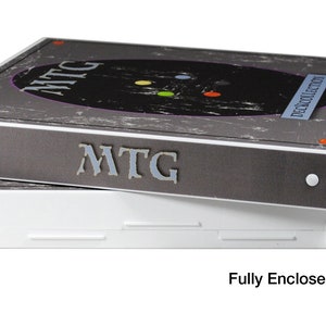 May include: Two grey and white storage boxes with the text "MTG" and "Deck Collection" on the top box. The boxes are stacked on top of each other. The bottom box is white and has a latch on the side. The text "Fully Enclosed Case" is below the boxes.