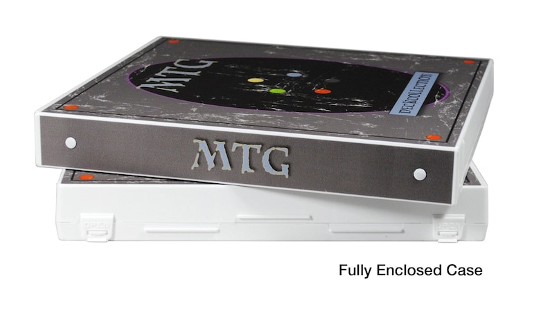 May include: Two grey and white storage boxes with the text "MTG" and "Deck Collection" on the top box. The boxes are stacked on top of each other. The bottom box is white and has a latch on the side. The text "Fully Enclosed Case" is below the boxes.