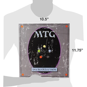 May include: A grey and black Magic: The Gathering Deck Collection box with a purple oval and the text "MTG DECK COLLECTION". The oval has five coloured dots in the centre.