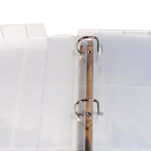May include: A white plastic binder with two silver rings. The binder is open and the pages are blank.