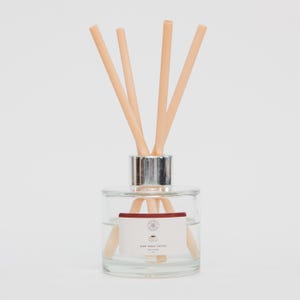 May include: A clear glass diffuser bottle with a silver collar and beige reeds. The bottle contains a liquid and a label that reads "Dark Roast Coffee". The diffuser is designed for home fragrance.