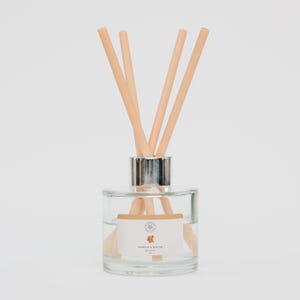 May include: A clear glass diffuser bottle with a silver collar and several light brown reeds. The bottle contains a clear liquid and a label that reads "Tobacco & Nectar". The reeds are arranged in a fan shape.