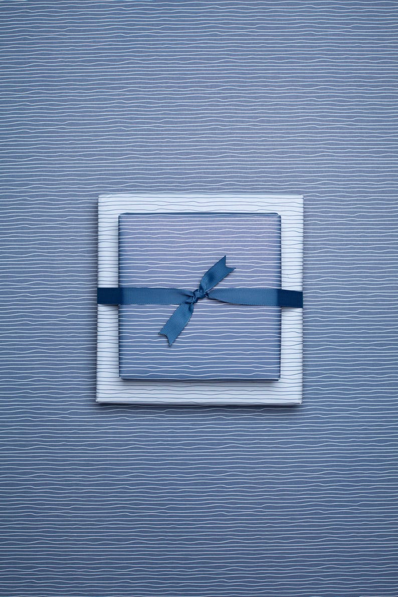 May include: Two gift boxes wrapped in blue and white striped paper, tied with a blue ribbon. The boxes are stacked on a blue background with a similar striped pattern.