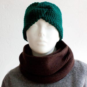 May include: A knitted dark teal turban-style hat and a brown infinity scarf are displayed on a mannequin. The hat is made of a chunky knit and the scarf is a solid color. The mannequin is wearing a gray sweater.