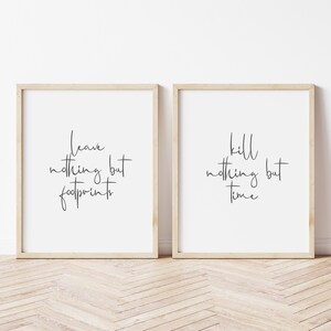 May include: Two framed prints with black calligraphy on white paper. The left print says "leave nothing but footprints". The right print says "kill nothing but time".