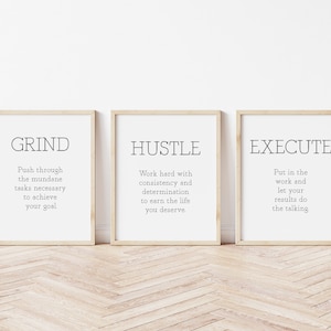 May include: Three framed motivational posters with the words "Grind", "Hustle", and "Execute" and short descriptions of each word. The posters are on a light wood floor.