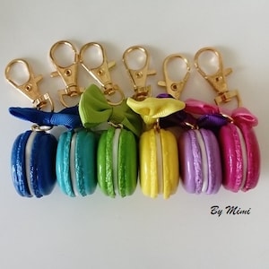 Puede incluir: Seis llaveros de macarons coloridos con cierres de langosta dorados y lazos. Los macarons son azules, verde azulado, verdes, amarillos, morados y rosas.