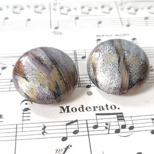 Könnte beinhalten: Ein Paar runde Ohrringe in Silber, Gold und Braun mit einem strukturierten, abstrakten Design.