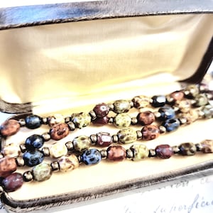 May include: A multi-strand necklace made of brown, green, and blue speckled beads in a velvet-lined box.