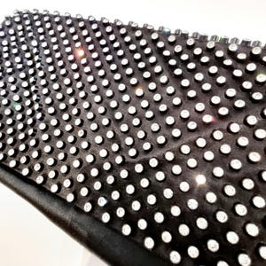 Könnte beinhalten: Schwarze Clutch-Tasche, die mit kleinen, klaren Strasssteinen besetzt ist.